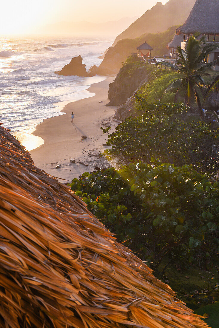 Young woman walking on the beach in front of Finca Barlovento at sunset, Tayrona National Park, Colombia