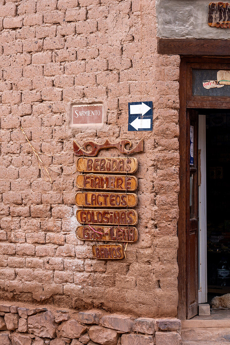 Carved wooden signs on the wall of a store in a traditional adobe brick building in Purmamarca, Argentina.