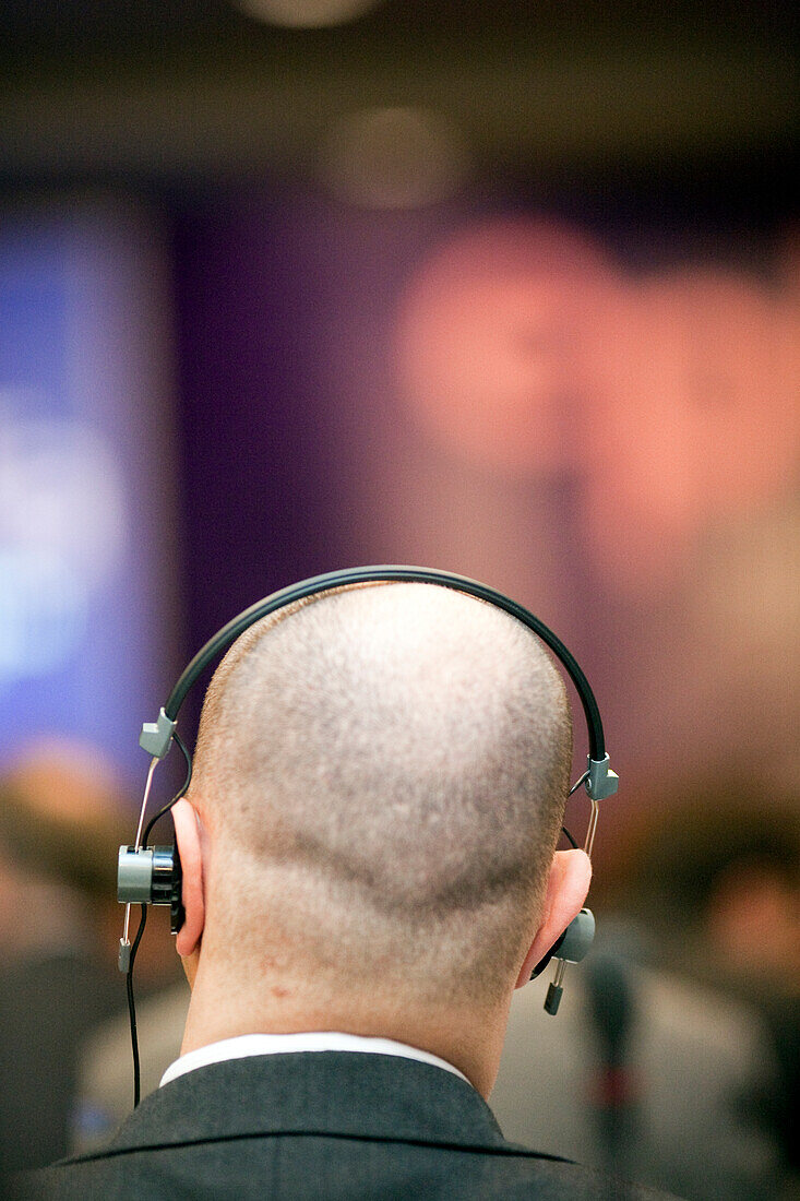 A man actively engages in a conference in Dublin, using headphones for translation services.