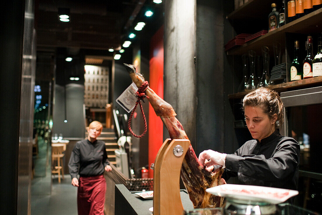 Barcelona, Spain, Sept 4 2008, A chef expertly slices Iberian ham while other staff observe in a sleek, modern restaurant setting in Barcelona, Spain.