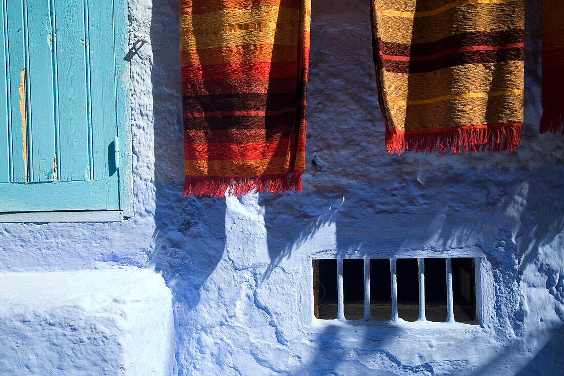 Farbenfrohe Teppiche hängen vor den Geschäften in der lebhaften Stadt Chefchaouen und zeigen die lokale Handwerkskunst und Kultur