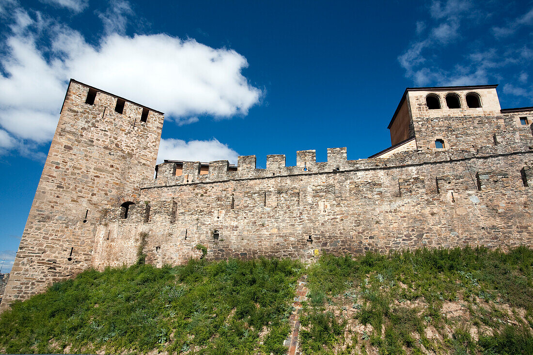 Discover the impressive walls of Castillo del Temple, showcasing medieval architecture under a bright blue sky in Ponferrada.