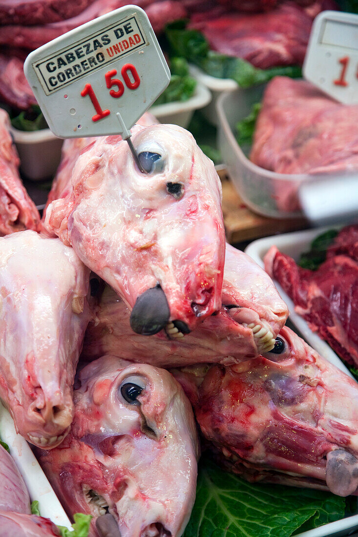 A close view of lamb heads displayed for sale at Mercat de la Boqueria, highlighting the vibrant market life in Barcelona.