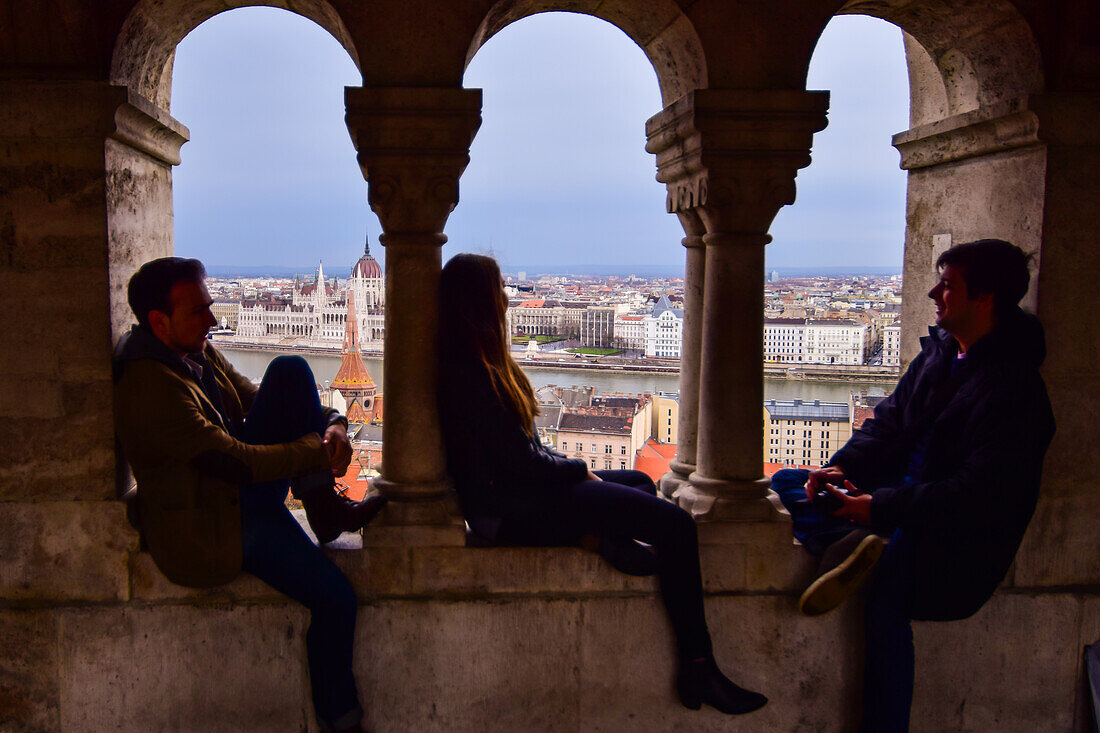 Tourists enjoy the view of Parliament building, Chain Bridge and Danube River through old columns, Budapest, Hungary, Europe