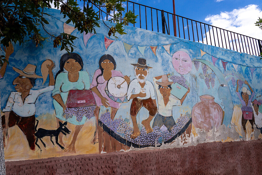 A wall mural depicting people crushing grapes with their feet to make wine in Cafayate, Argentina.