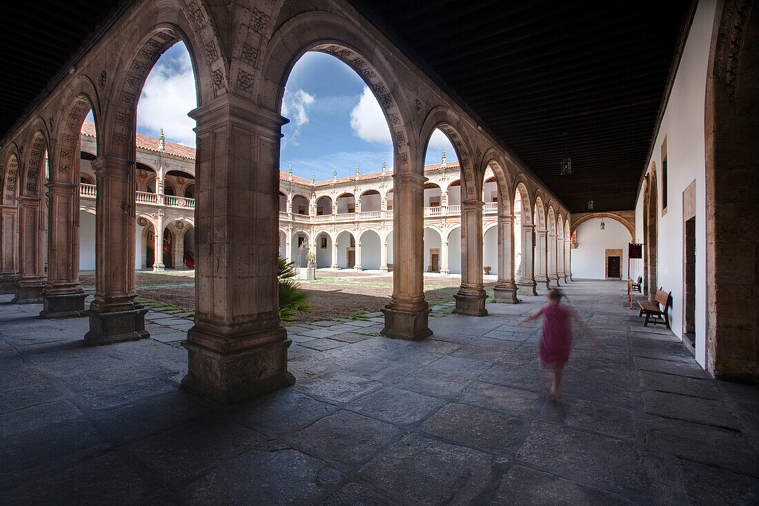 Salamanca, Spanien, 17. August 2008, Ein Besucher spaziert durch den historischen Kreuzgang des Colegio Arzobispo Fonseca und genießt die heitere Architektur und den klaren blauen Himmel