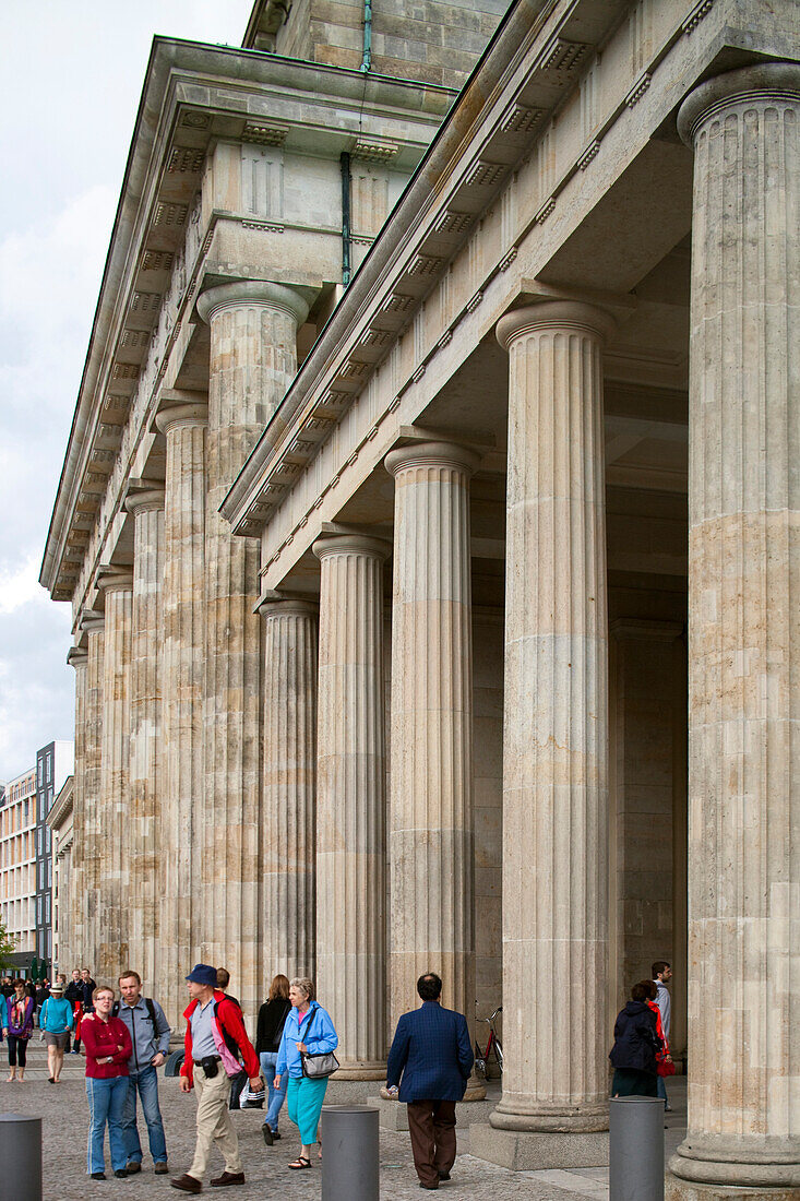 Berlin, Germany, July 24 2009, People walk by the impressive columns of the Brandenburg Gate, a famous landmark in central Berlin, Germany, on a vibrant day.