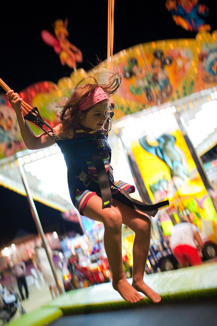 Ein kleines Kind springt während eines vergnüglichen Abends in Sanlucar de Barrameda fröhlich auf einem Bungy-Trampolin herum