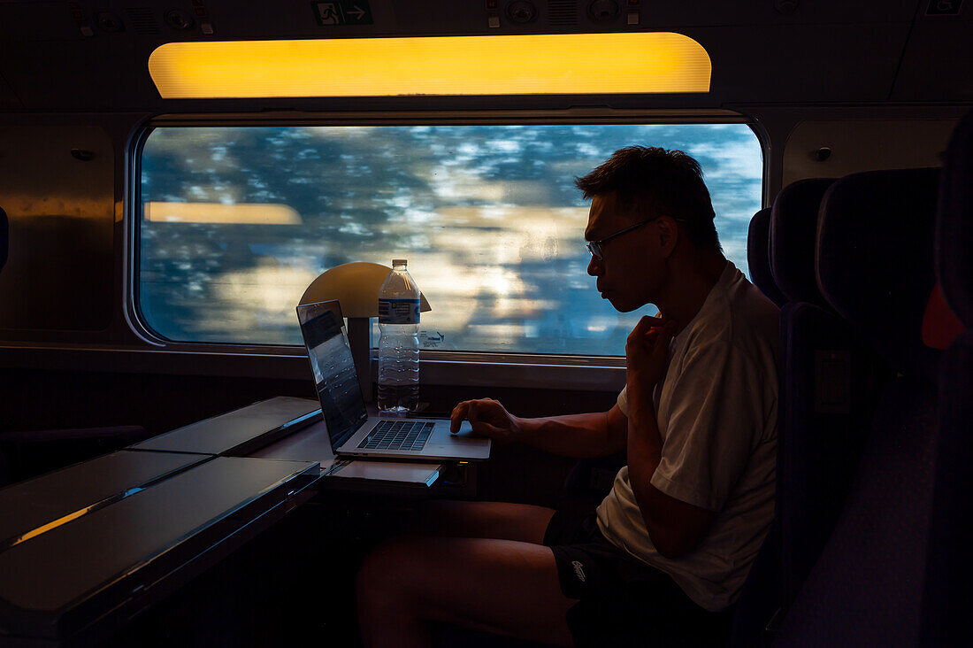 Silhouette of man working with his laptop in the high speed AVE train, Spain