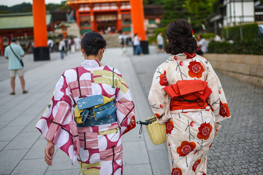 Zwei junge Frauen in traditioneller japanischer Kleidung und das Torii-Tor von Fushimi Inari, Kyoto, Japan