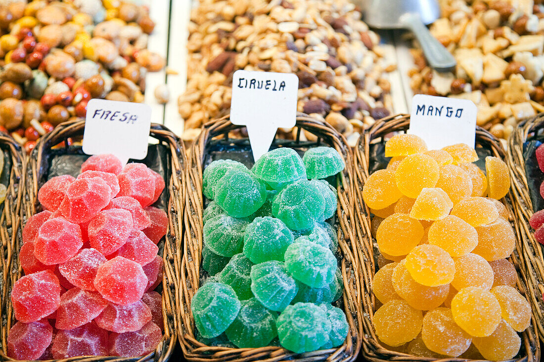 Brightly colored candies are artfully arranged in baskets at Mercado de la Boquería, inviting visitors to indulge in sweet treats.