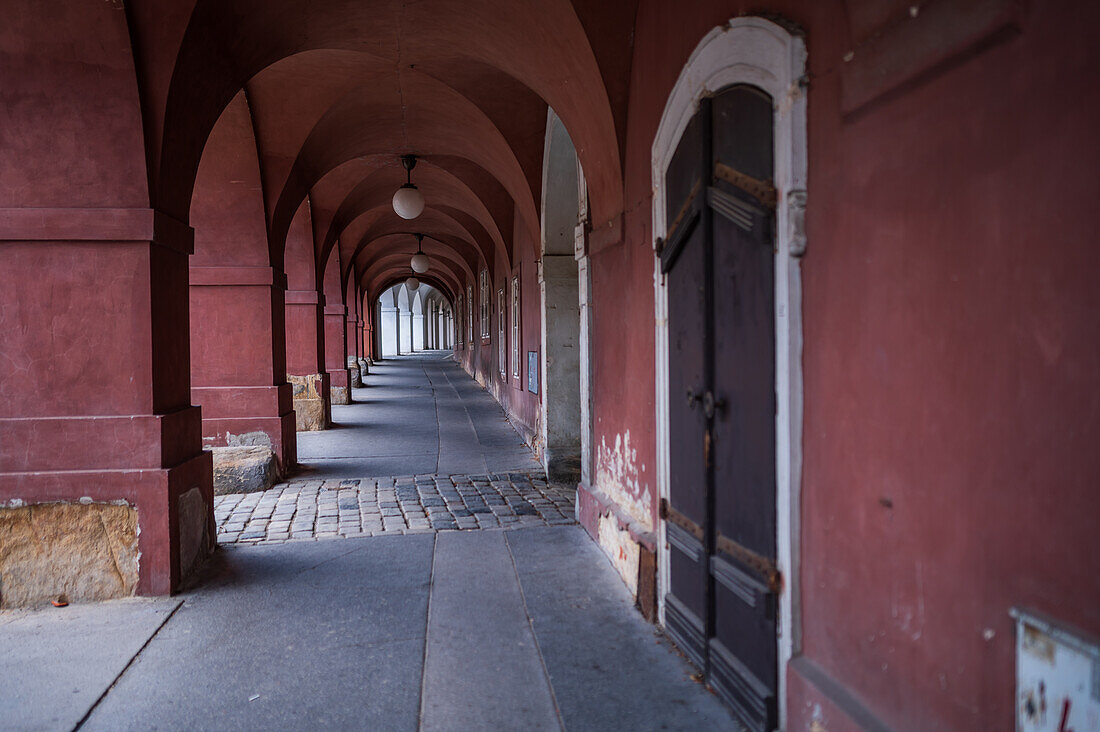 Ein schmaler bogenförmiger Durchgang in der Prager Altstadt, dunkelrot gestrichen