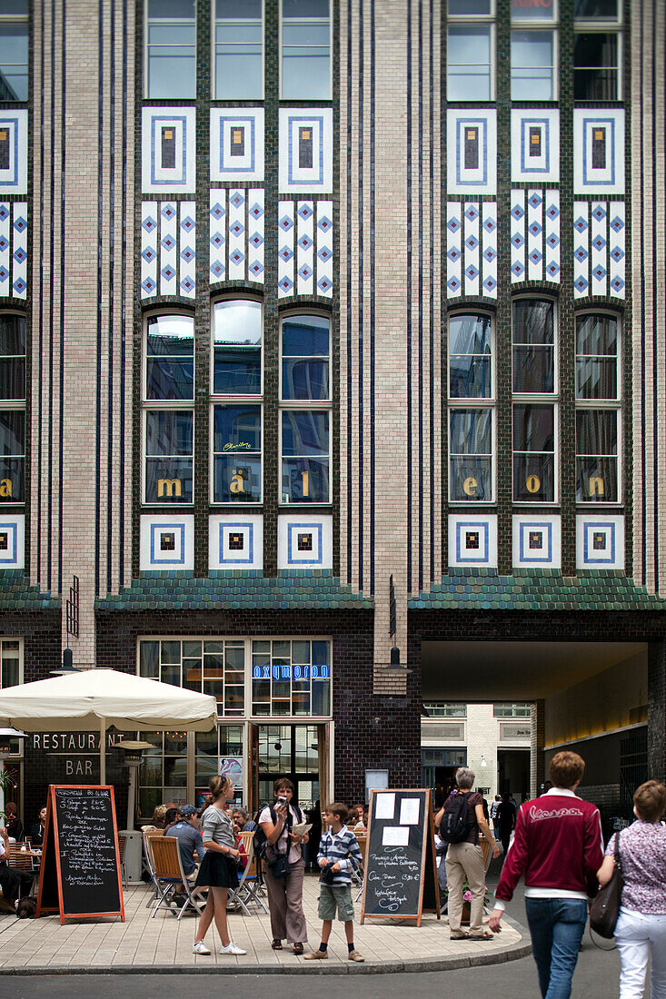 Visitors explore the distinctive Art Nouveau courtyard of Hackeschen H?fe in Berlin, surrounded by unique glazed ceramic designs.