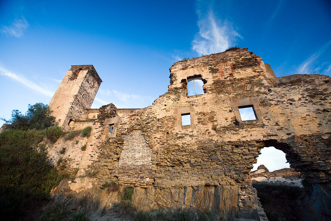 Die Überreste des Klosters Monjas Comendadoras zeigen verwitterte Steinmauern vor einem strahlend blauen Himmel in Alcántara, Extremadura