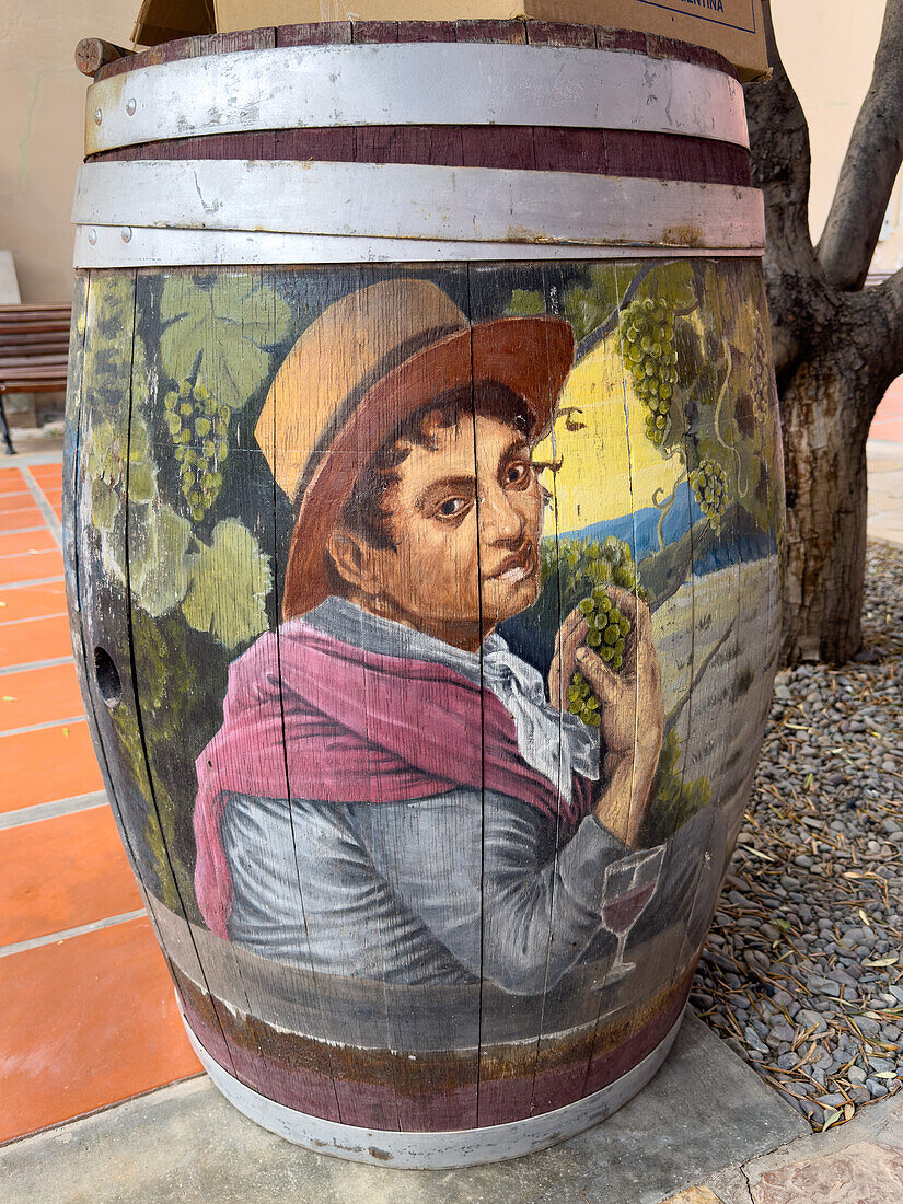 Painted wine barrel in the courtyard of the Museo de la Vid y el Vino or Museum of the Vine and the Wine in Cafayate, Argentina. The painting has a wine-making motif.