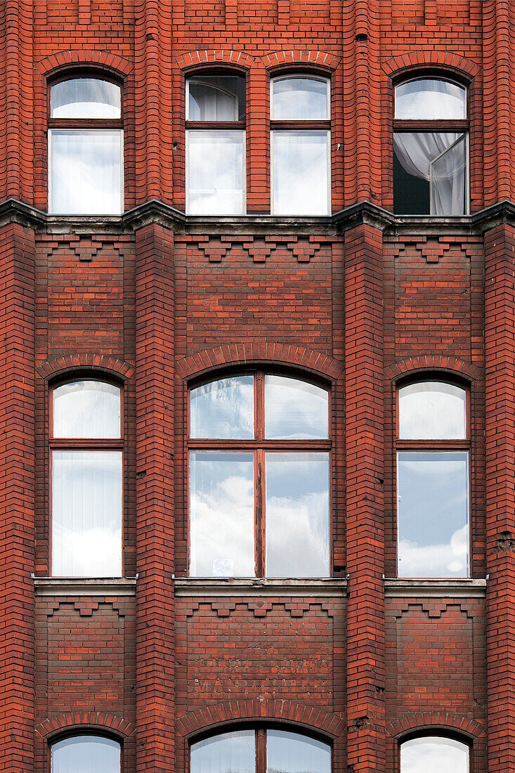 Die markante rote Backsteinfassade in Berlin-Mitte mit ihren großen Fenstern, in denen sich der Himmel spiegelt, zeugt von einem reichen architektonischen Erbe