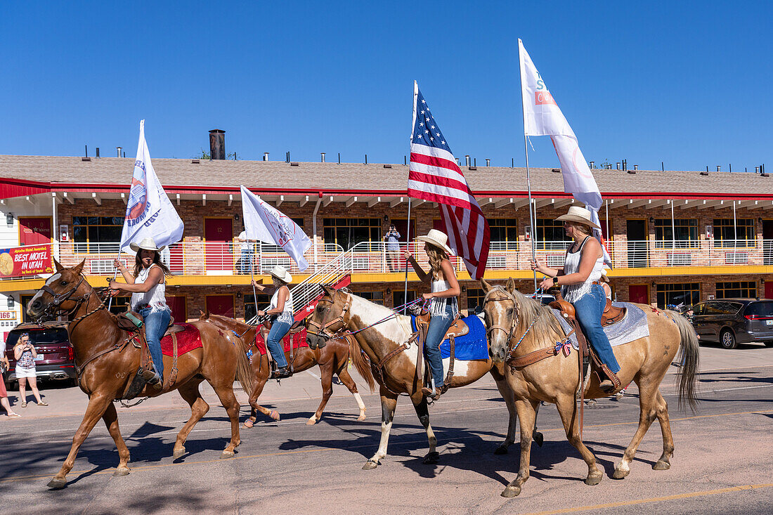 An equestrian drill team on horseback with an American flag in the Fourth of July Parade on Independence Day in Moab, Utah.