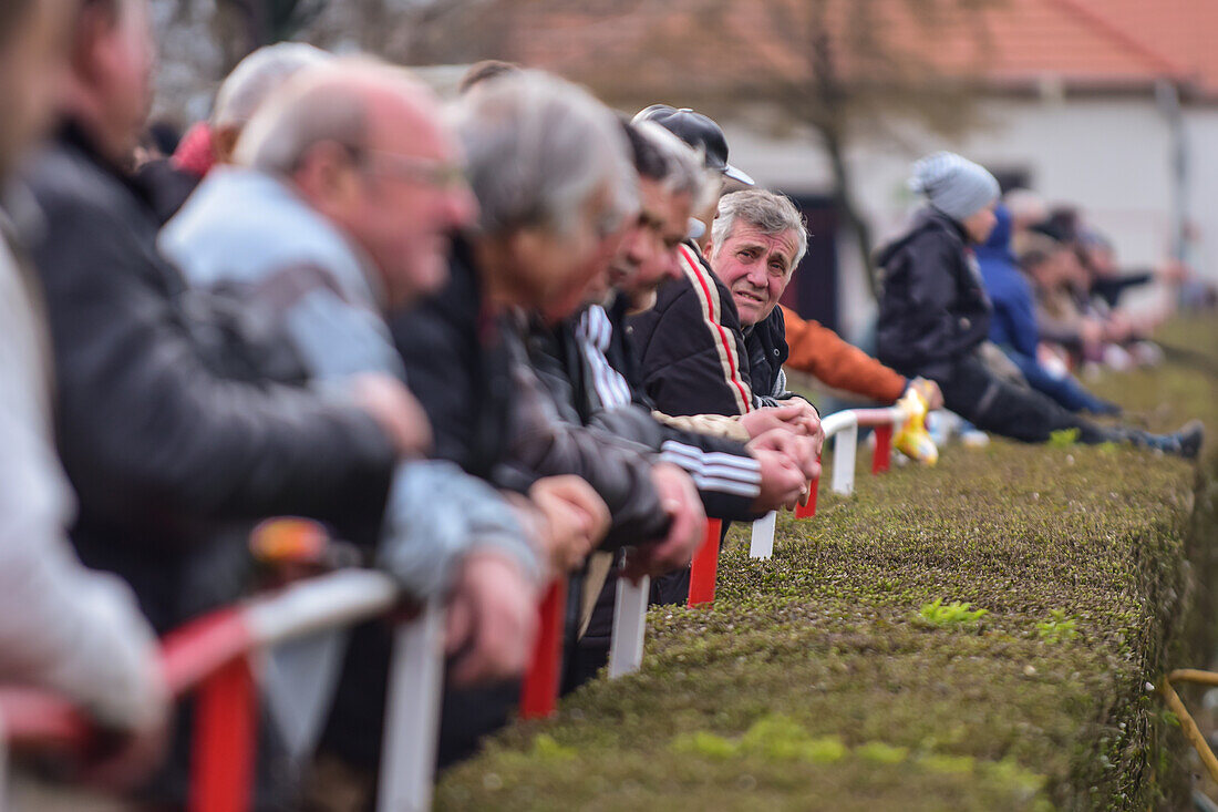 People watching a soccer youth game in small town of Hungary