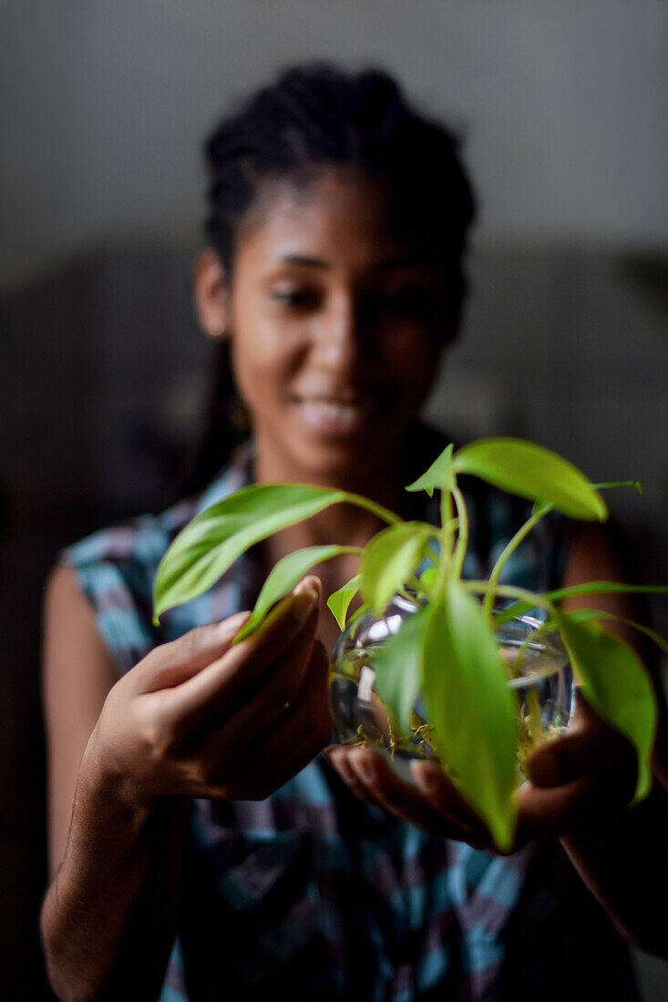 Young afro latin woman gardening and holding an hydroponic plant