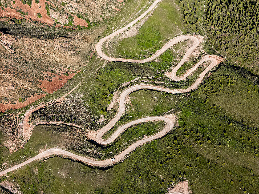 Luftaufnahme einer kurvenreichen Bergstraße, Kalmak-Ashuu-Pass, durch üppiges Grün in Kirgisistan, Zentralasien, Asien