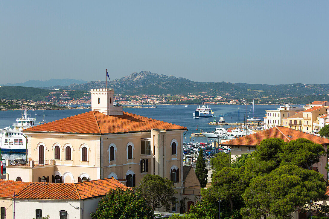 View across tiled rooftops to distant Palau, the Palazzo dell'Ammiragliato (Admiralty), prominent in foreground, La Maddalena, La Maddalena Island, La Maddalena Archipelago National Park, Sassari, Sardinia, Italy, Mediterranean, Europe