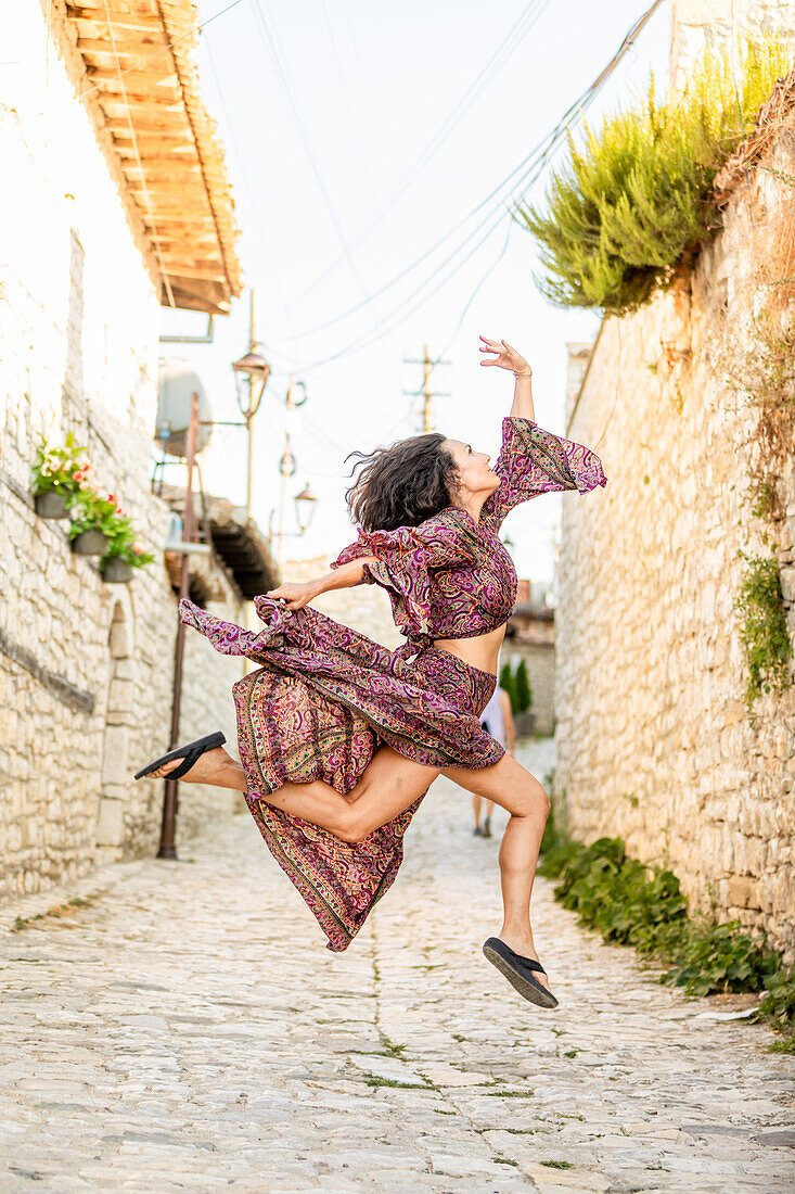 Woman jumping on the street in Berat, Albania, Europe