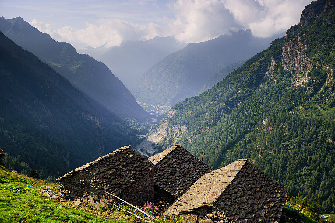 Naturpark Valsesia und das Alta Val Strona mit Blick über das Tal mit Steindächern traditioneller Hütten im Vordergrund, Piemont, Italienische Alpen, Italien, Europa