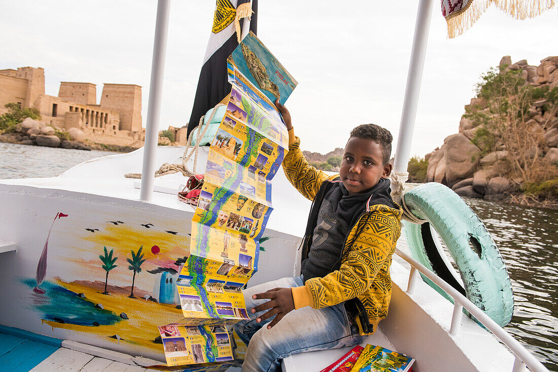 Junger Reiseführer-Verkäufer an Bord eines Touristenbootes auf dem Weg zum Tempel der Isis, Tempel von Philae, Agilkia-Insel, Assuan, Ägypten, Nordafrika, Afrika