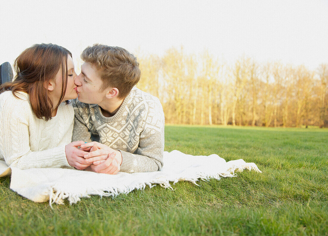 Young Couple lying on Grass Kissing