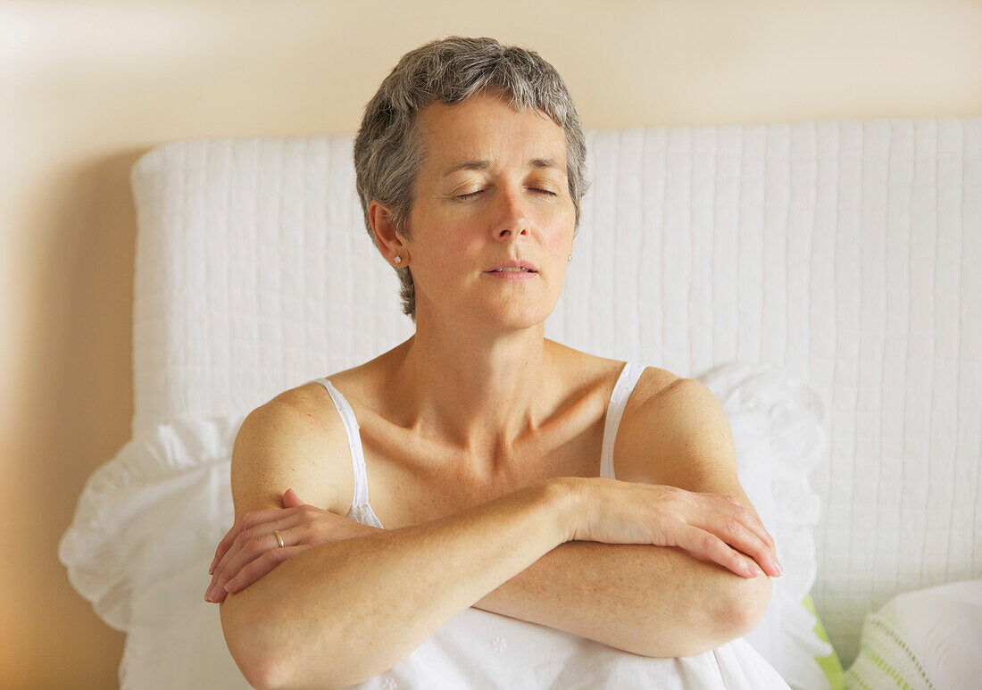 Woman Sitting in Bed with Arms Crossed