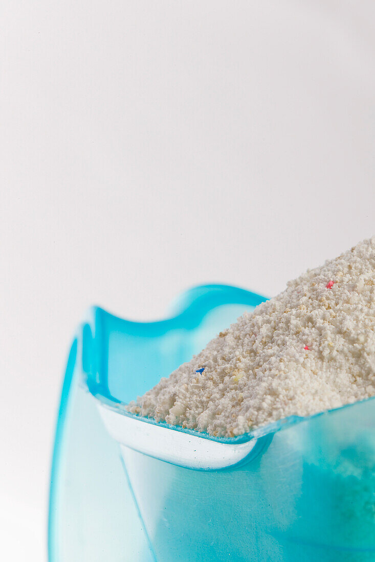 Close up of a plastic measuring jug filled with washing powder