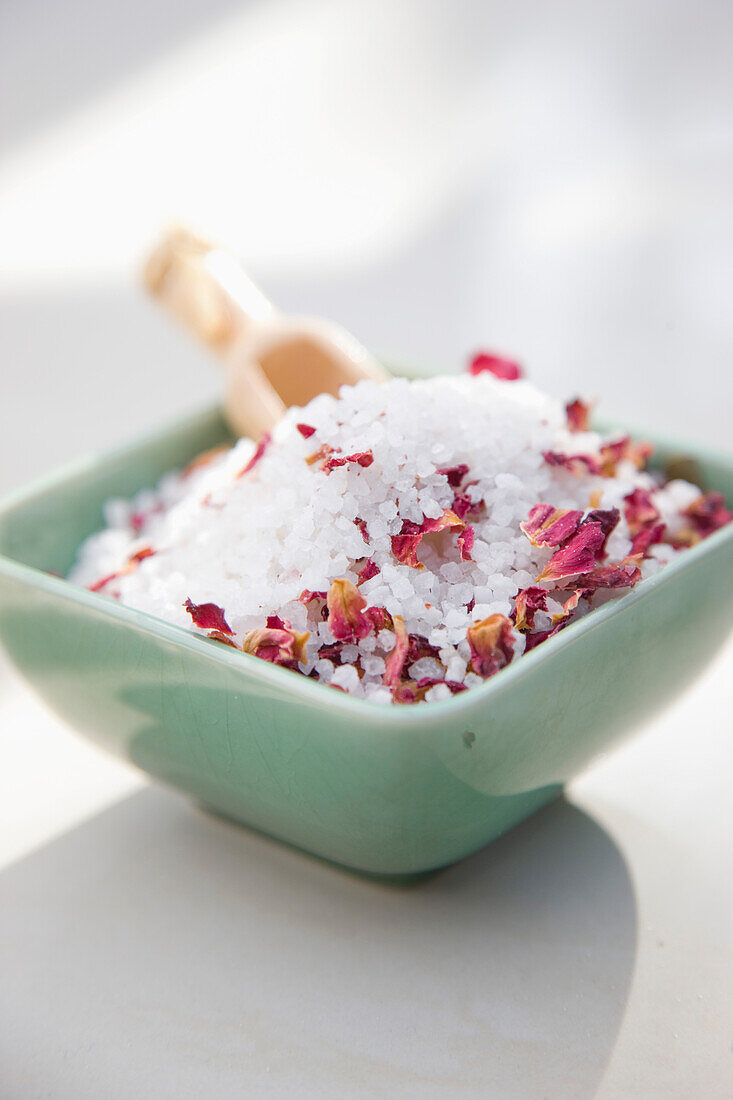 Close up of a ceramic bowl filled with bath salts and petals