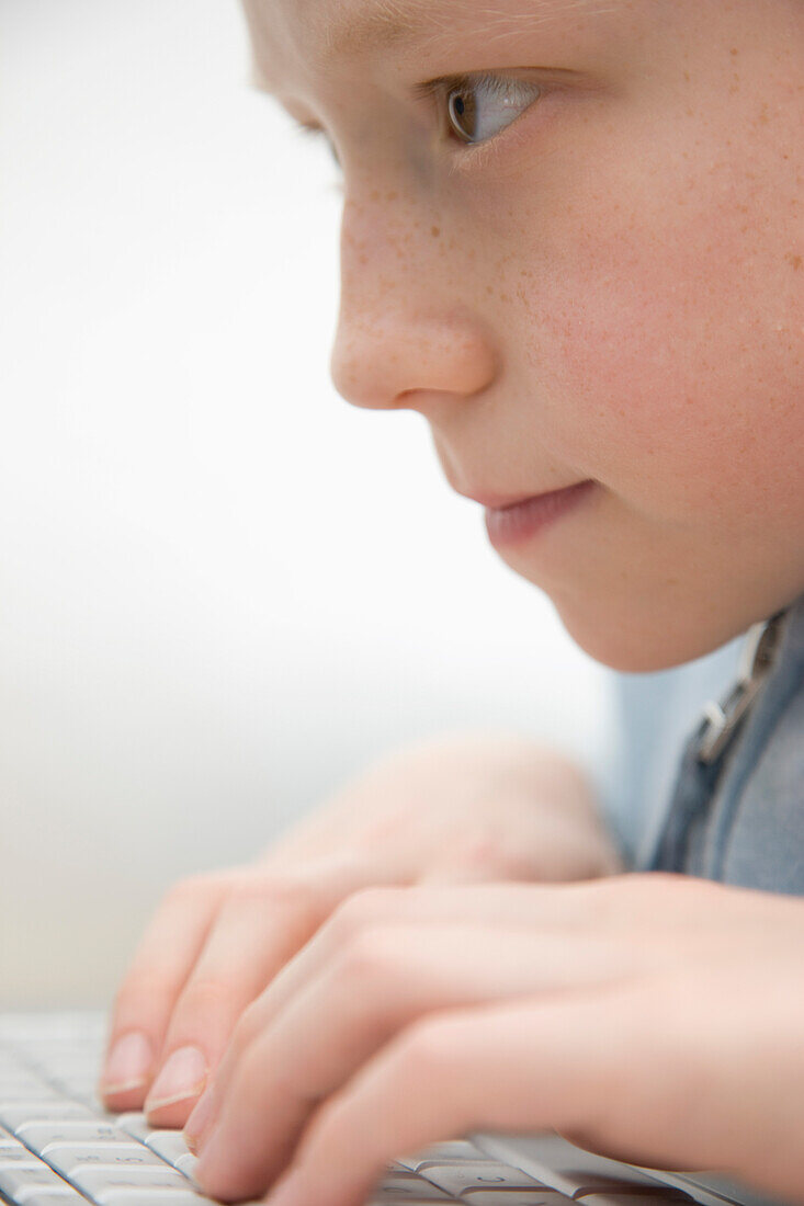 Extreme close up of a boy typing on laptop computer keyboard