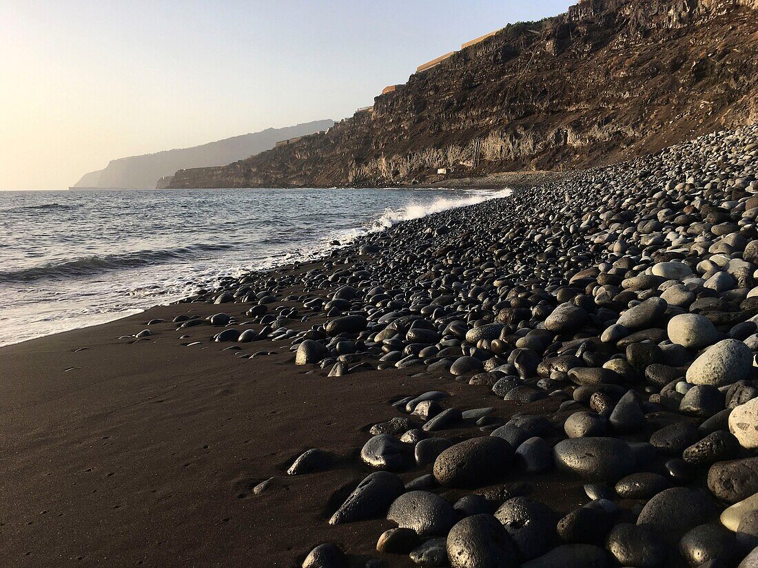 Spain, Canary Islands, Palma Island, Playa Nueva, black sand and pebble beach at the foot of a cliff occupied by banana plantations