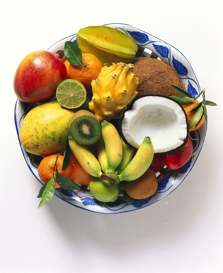 Exotic fruits with halved coconut on plate
