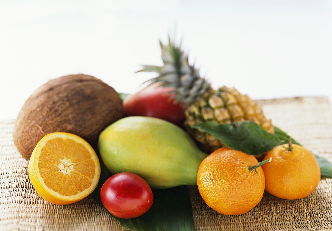 Exotische Früchte, Mandarinen und Kokosnuss auf einer Matte