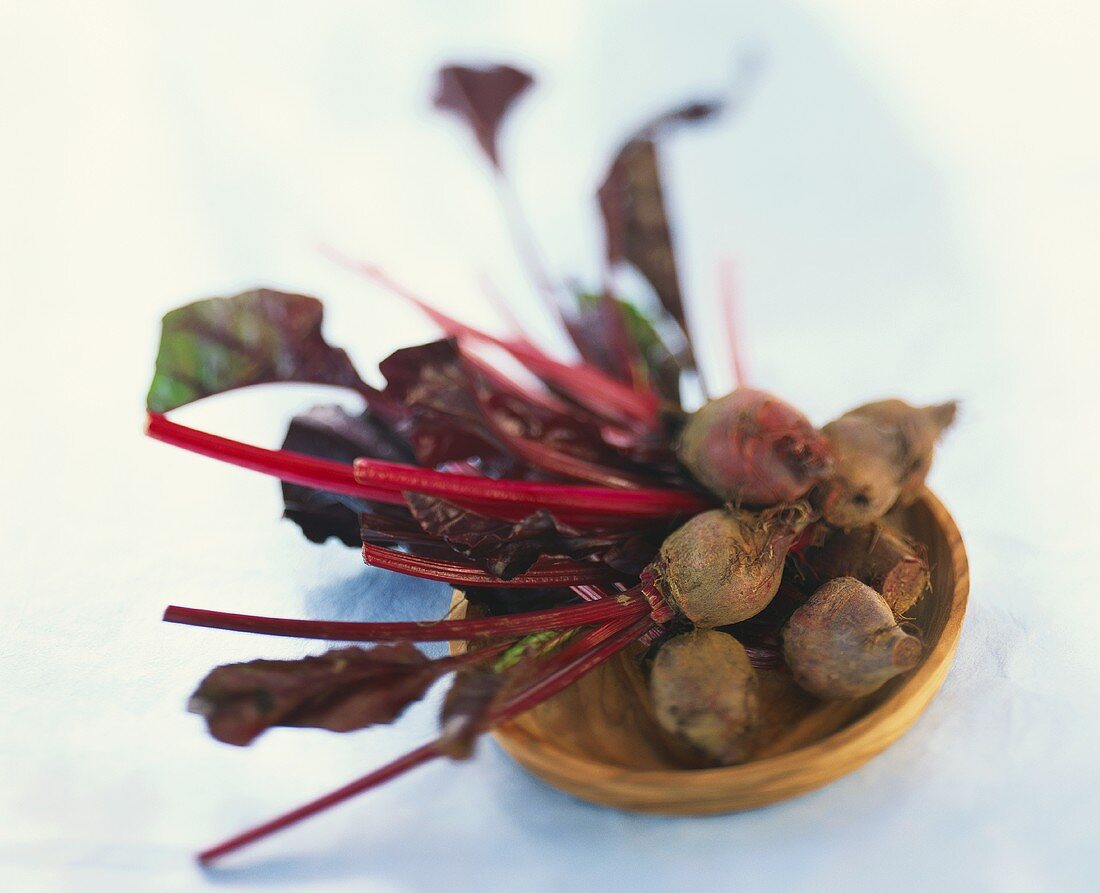 Einige Rote-Bete-Knollen mit Blättern auf Teller