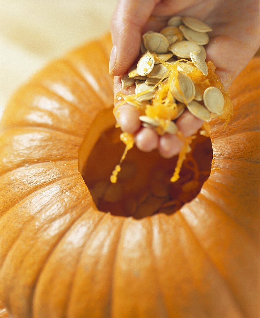 Hollowing out: hand taking seeds out of pumpkin