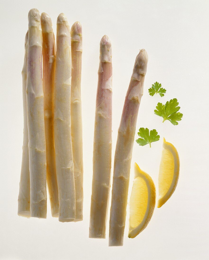 A few stalks of raw white asparagus with lemon wedges