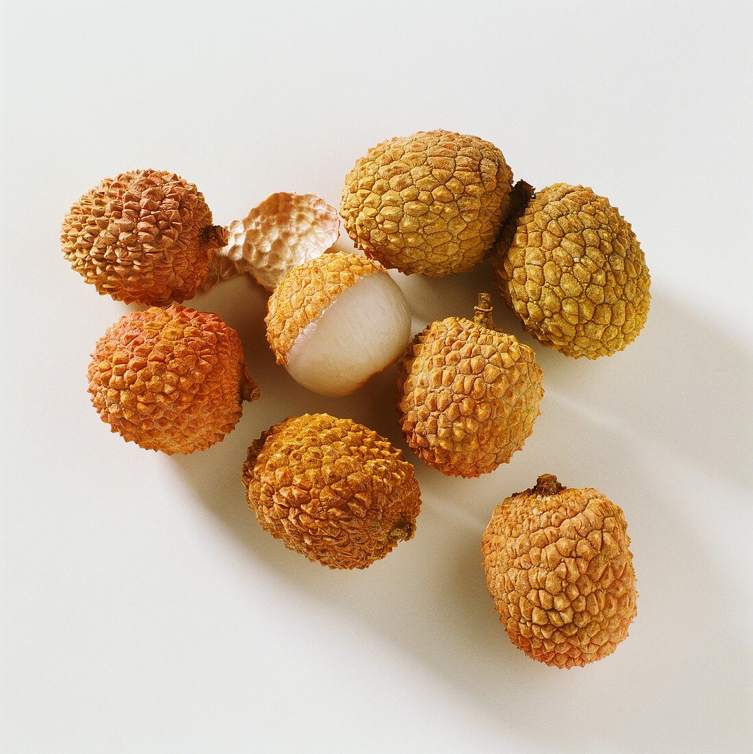 A few lychees with skin, one opened