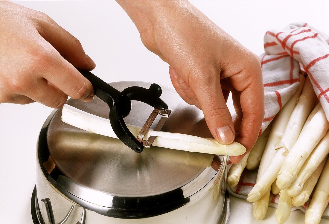 Peeling asparagus on pan bottom with vegetable peeler