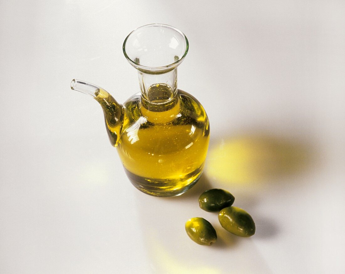 Carafe of olive oil and three green olives