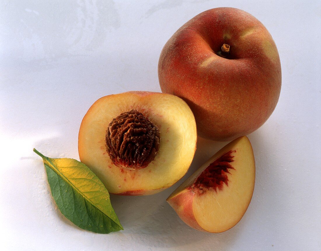 Whole and half peach, peach slice and leaf