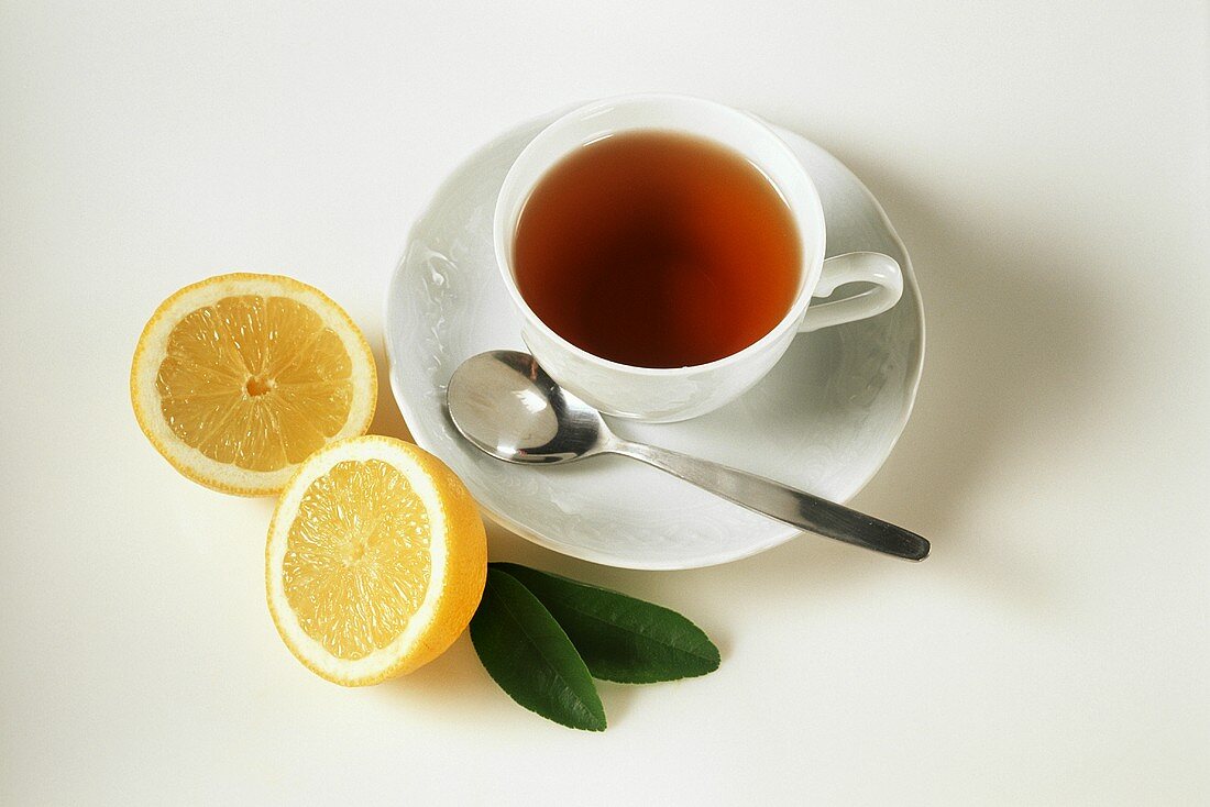 Eine Tasse Tee, daneben aufgeschnittene Zitrone
