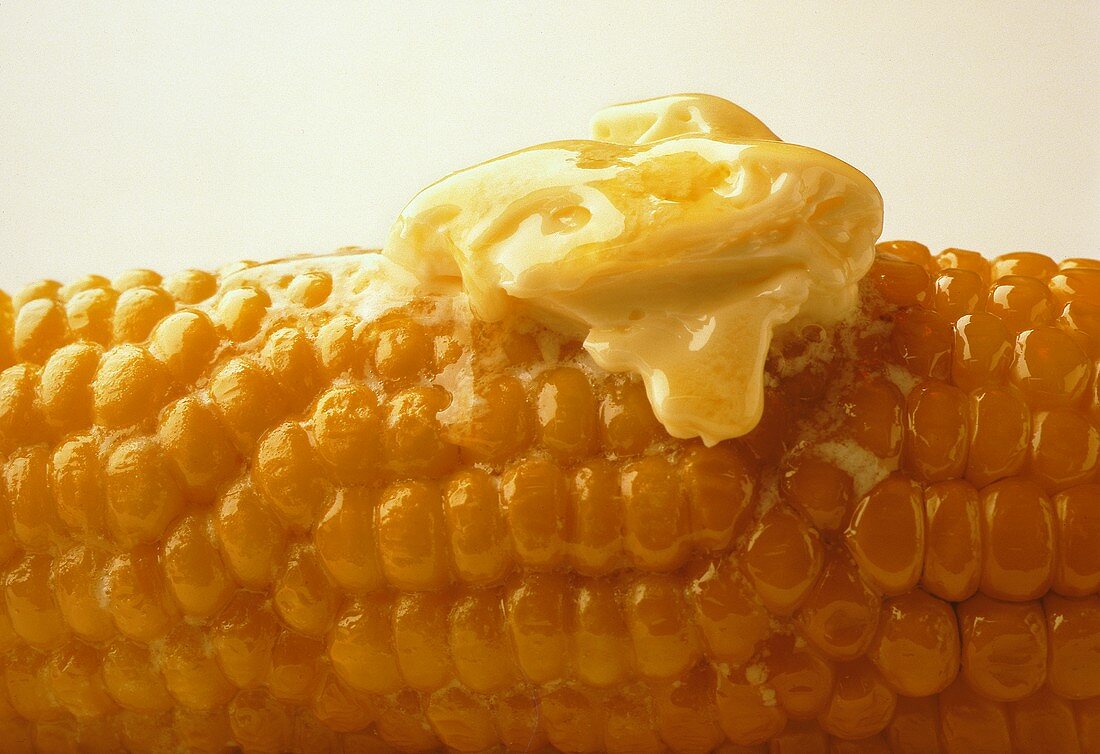 Gekochter Maiskolben mit einem Stück schmelzender Butter