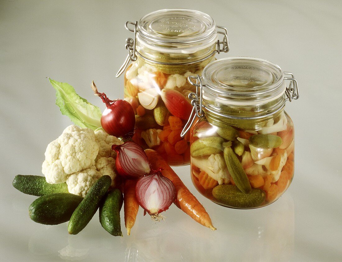 Zwei Gläser eingelegte Mixed Pickles, daneben frisches Gemüse