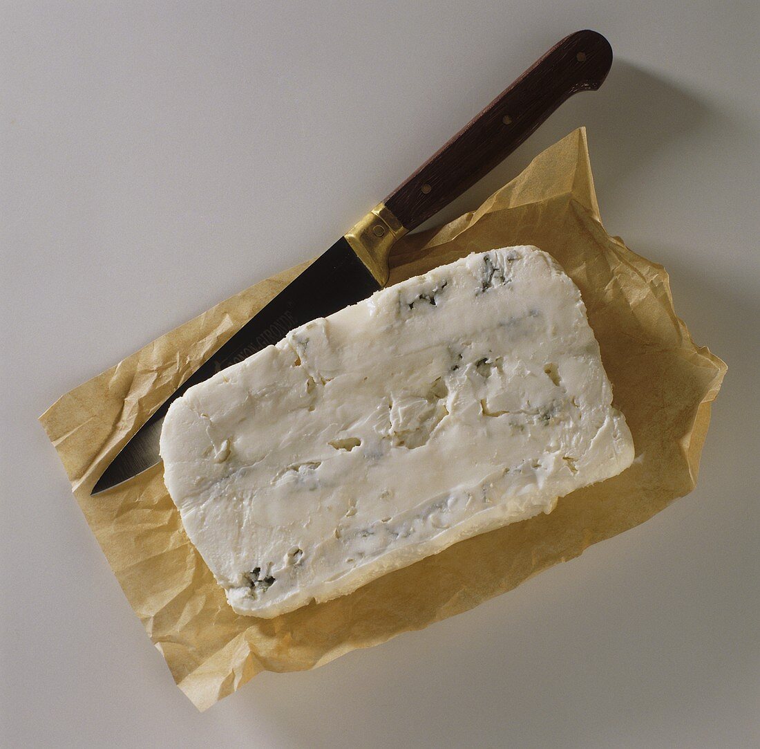 Ein Stück Gorgonzola auf Papier und ein Messer