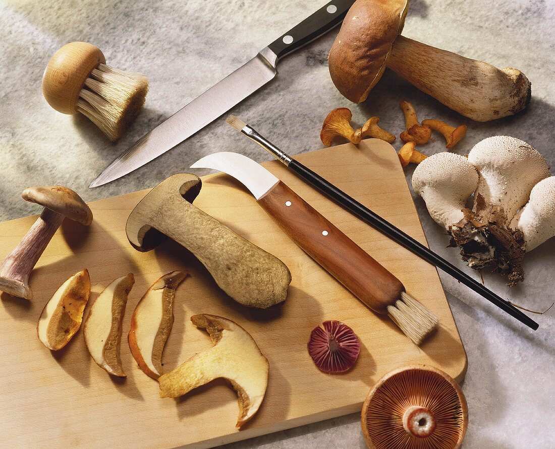 Mushroom slices on wooden board with knives & cleaning tool