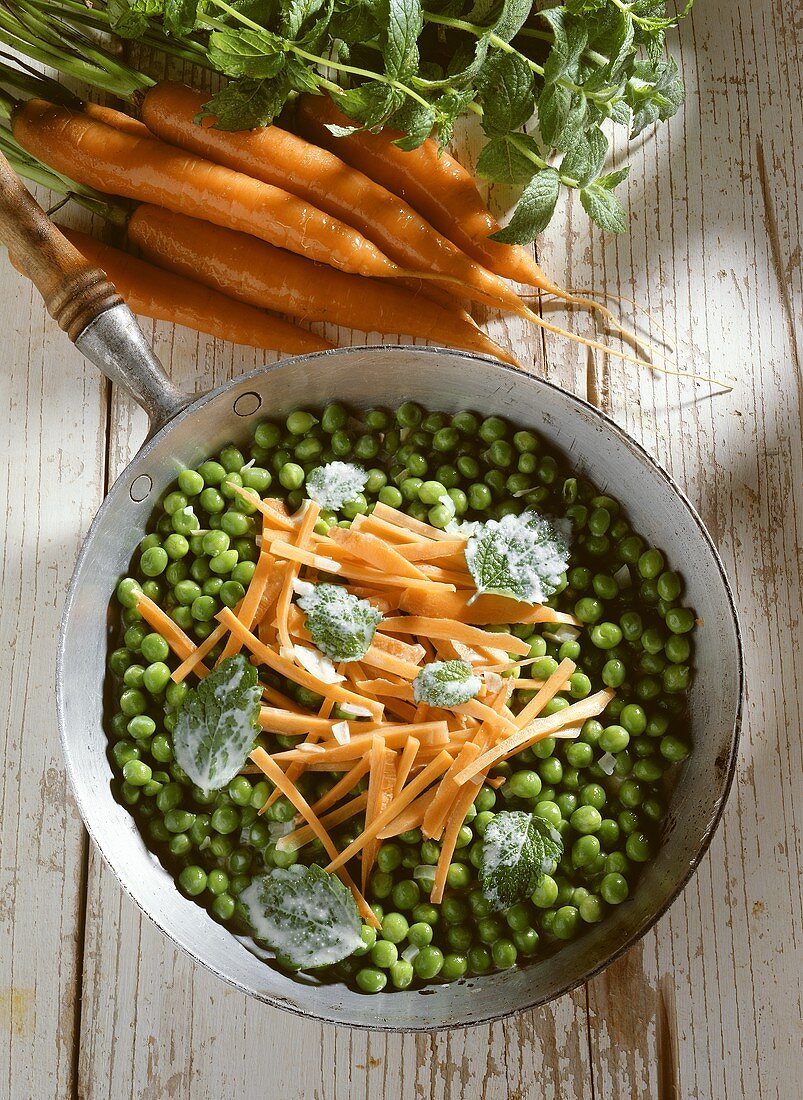Pea and carrot casserole & mint leaves in pan with handle