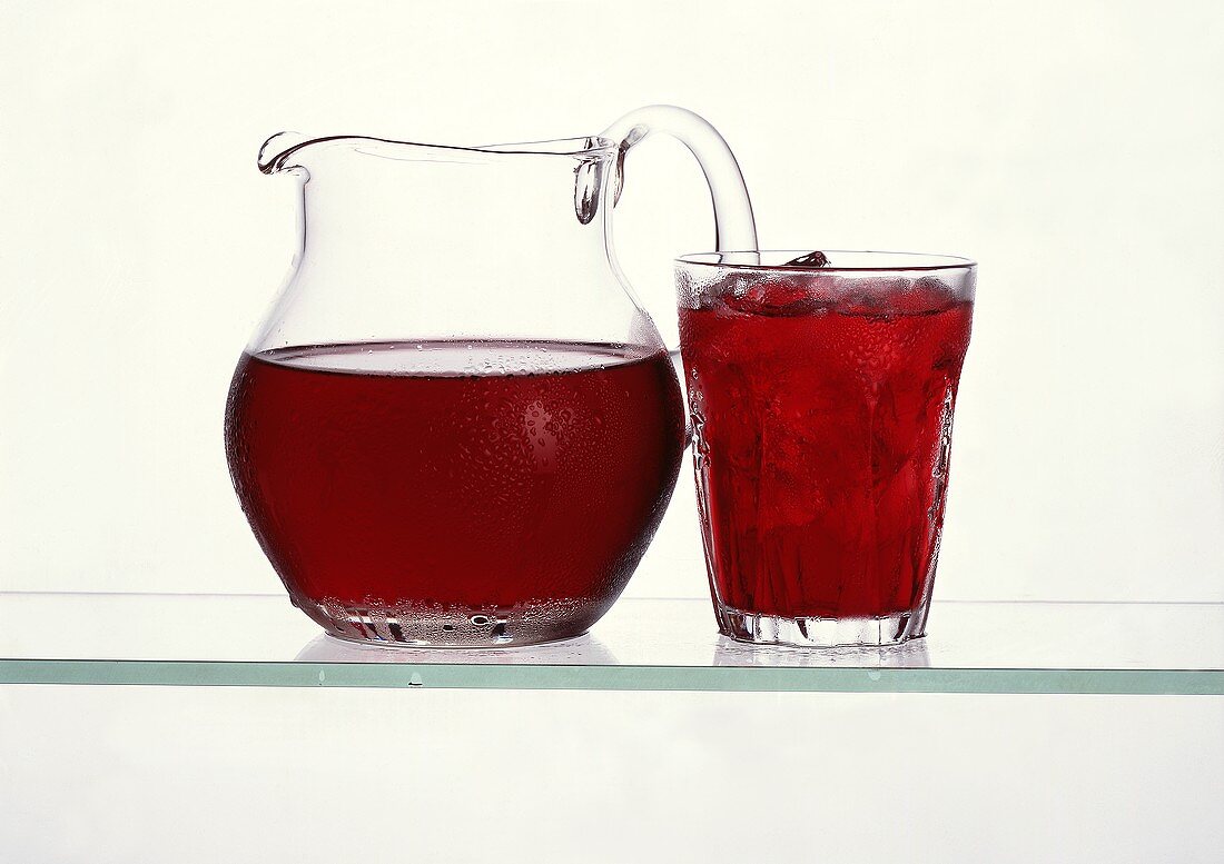 Cherry juice in glass jug & in glass with ice cubes